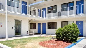 A multi-story motel with blue doors numbered 217, 220, 221, and 114. - 1 Full Bed | ADA/RI Shower (Bakersfield)