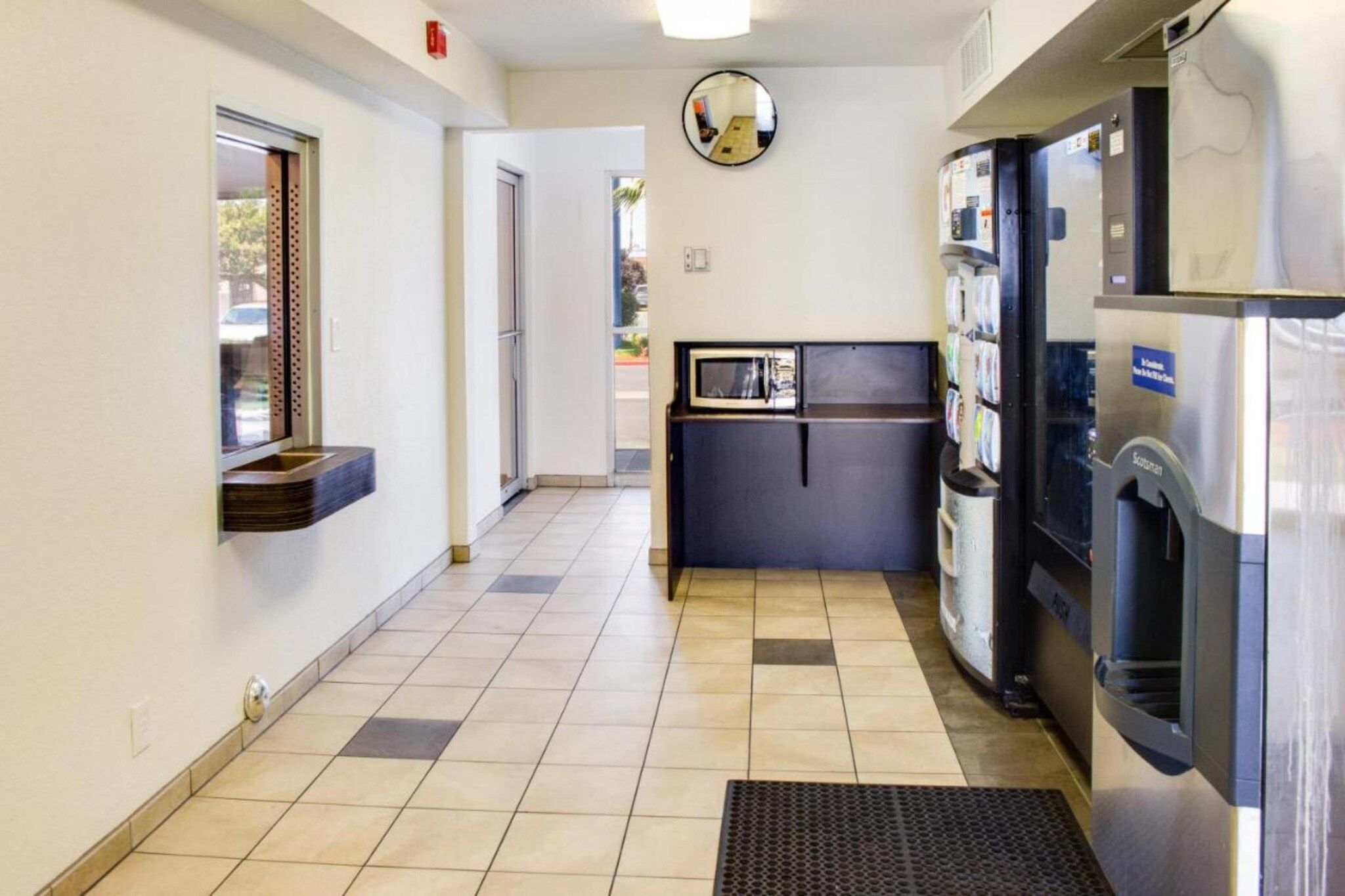 A hallway with a refrigerator, a microwave, and a water dispenser on the right.