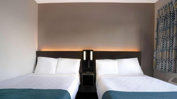 Een hotelkamer met twee bedden, een nachtkastje en een wandlamp.