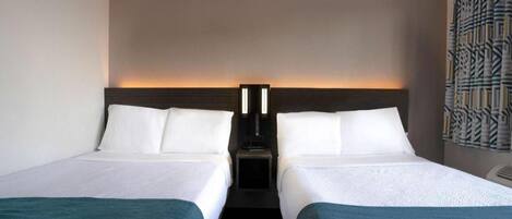A hotel room with two beds, a nightstand, and a wall-mounted light fixture.