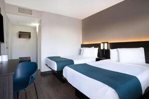 Habitación de hotel con dos camas, un escritorio y una silla.