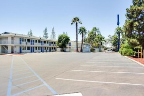 Ein Motel mit Parkplatz, mehrstöckigen Gebäuden und Palmen.