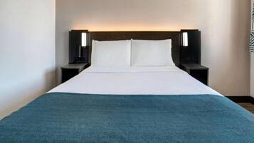A hotel room with a bed, two bedside tables, and a headboard.