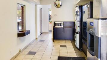 A hallway with a refrigerator, a microwave, and a water dispenser.