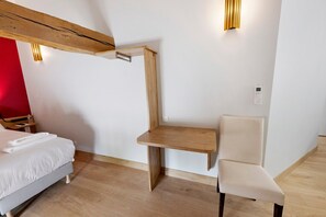 Ein Hotelzimmer mit einem Bett, einem Holztisch, einem Stuhl und einer Wandleuchte.