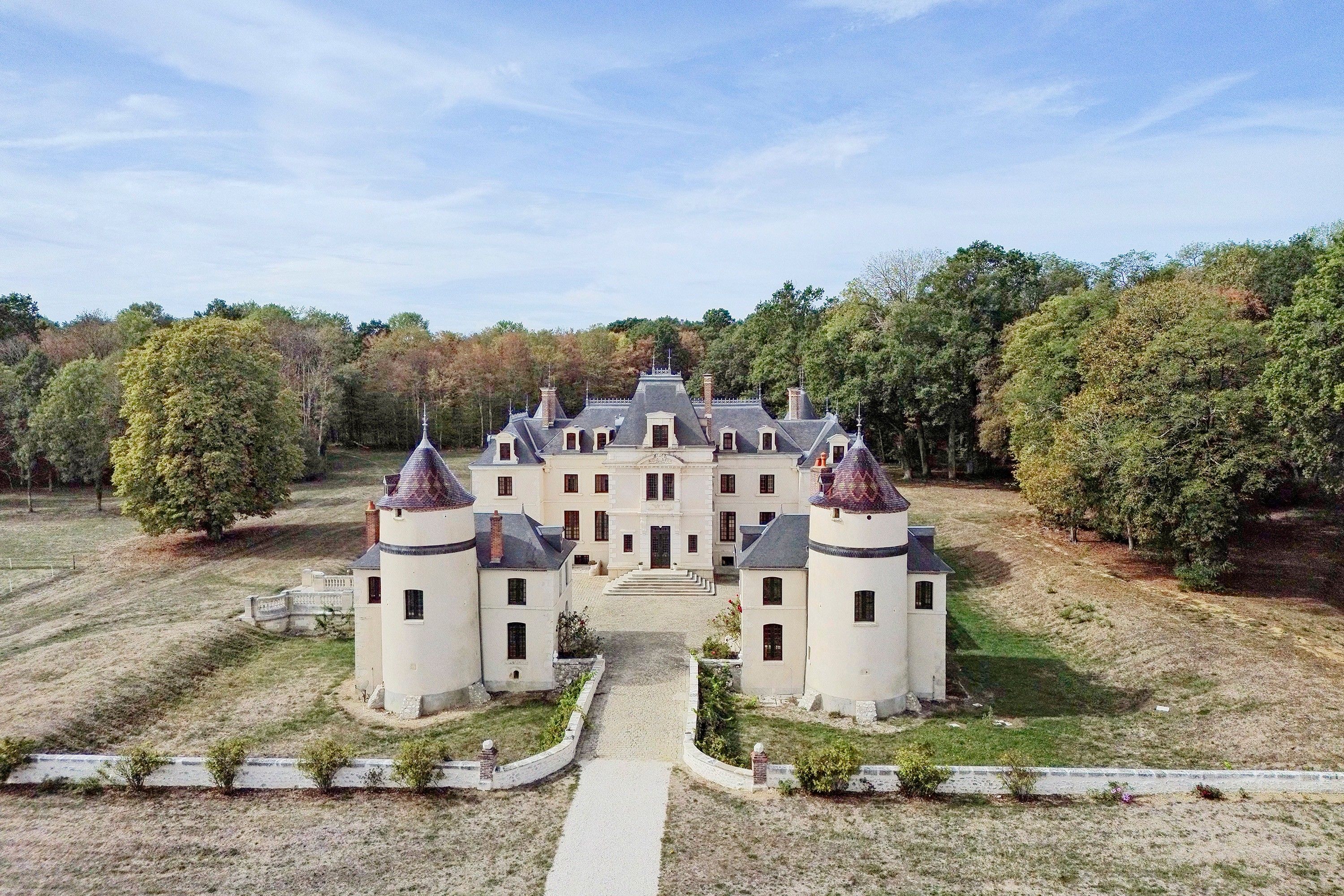 A large, symmetrical building with multiple towers and a central entrance, surrounded by a well-maintained lawn and trees.
