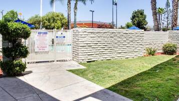 Zona de piscina amurallada con un cartel que indica ausencia de socorrista y normas de la piscina.