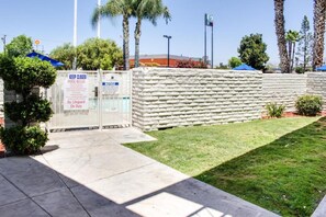 A gated pool area with a sign indicating no lifeguard on duty and pool rules.