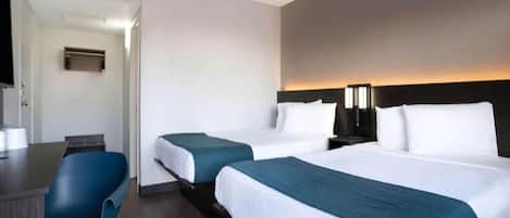 Habitación de hotel con dos camas, un escritorio y una silla.