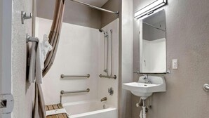 A bathroom with a bathtub, a shower, a sink, and a mirror. - Sunny 2 Full Beds | Smoking (Bakersfield)