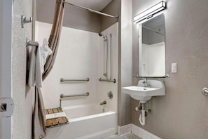 Un baño con bañera, ducha, lavamanos y espejo.