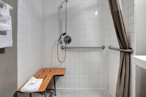 A shower area with a grab bar, a bench, and a towel rack.