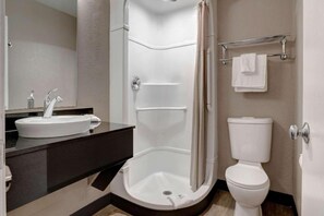 A modern bathroom with a shower, toilet, sink, and a mirror.