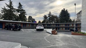 Un estacionamiento con dos autos, un edificio con un letrero que dice 'St. Luke's' y una fila de árboles.