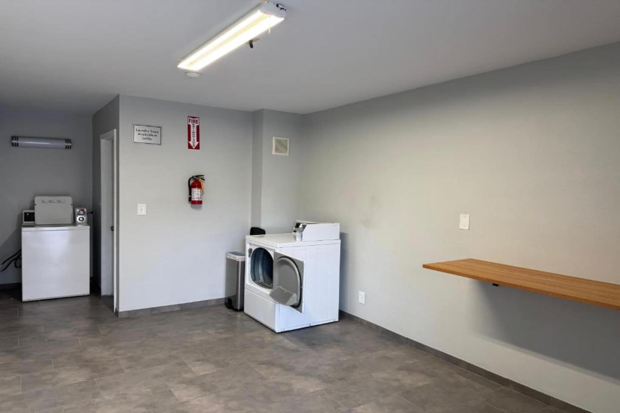 A laundry room with a washing machine, dryer, and a fire extinguisher on the wall.
