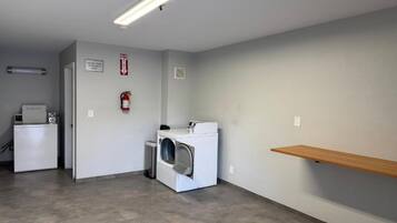 Une buanderie équipée d’un lave-linge, d’un sèche-linge et d’un extincteur fixé au mur.