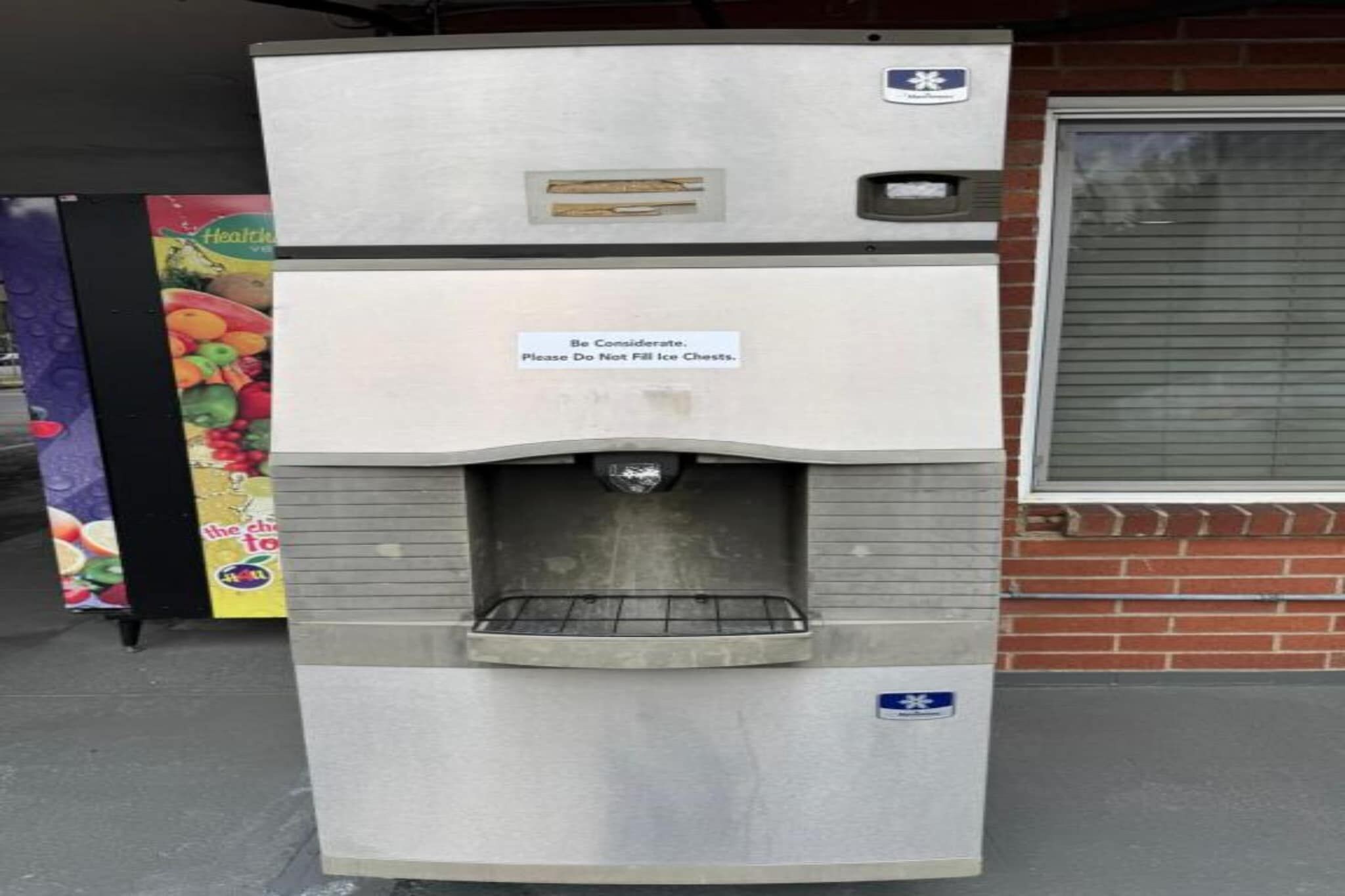 Máquina expendedora con un letrero que recomienda ser considerados y no llenar los contenedores de hielo.