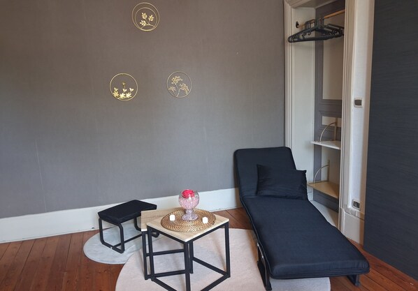 A room with a dark-colored sofa, a small table with a decorative item, a chair, and a wall with three circular wall art pieces.