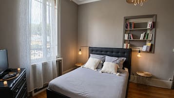 Un dormitori amb un llit, làmpades de nit, una estanteria i una televisió.