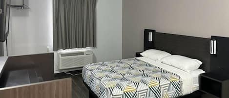 Hotelkamer met een bed, nachtkastje, airconditioning en een raam met gordijnen.