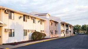 A row of two-story buildings with air conditioning units, a clear sky, and a parking lot. - 1 King Bed | Non-Smoking (Omaha NE)