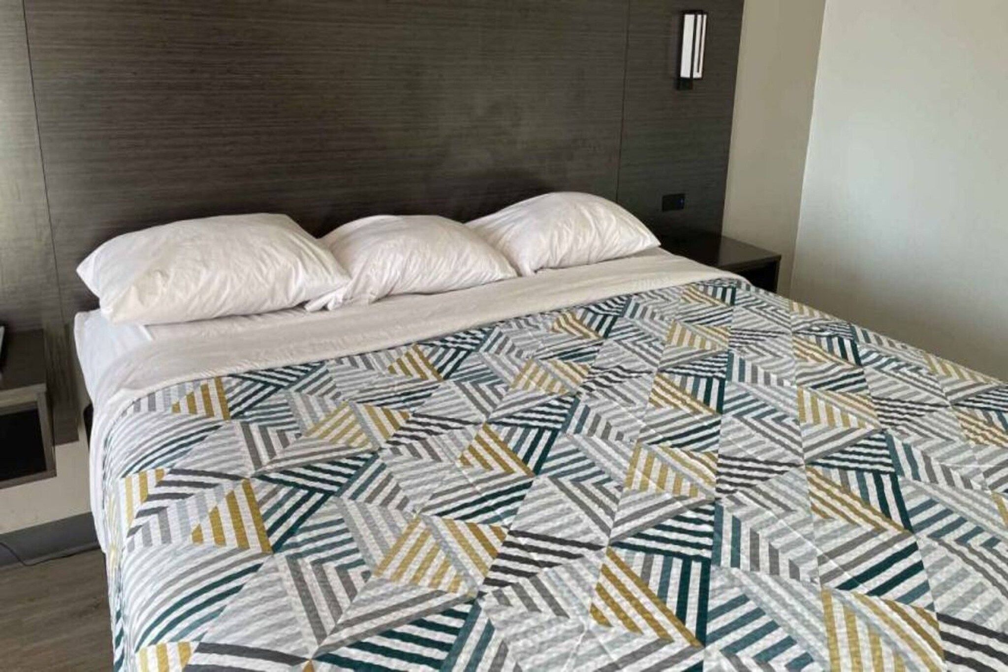 A bed with a patterned bedspread and two pillows.