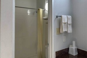 A bathroom with a shower, a towel rack with towels, and a toilet paper holder. - 1King Bed|Smoking, Micfridge (Stockbridge)