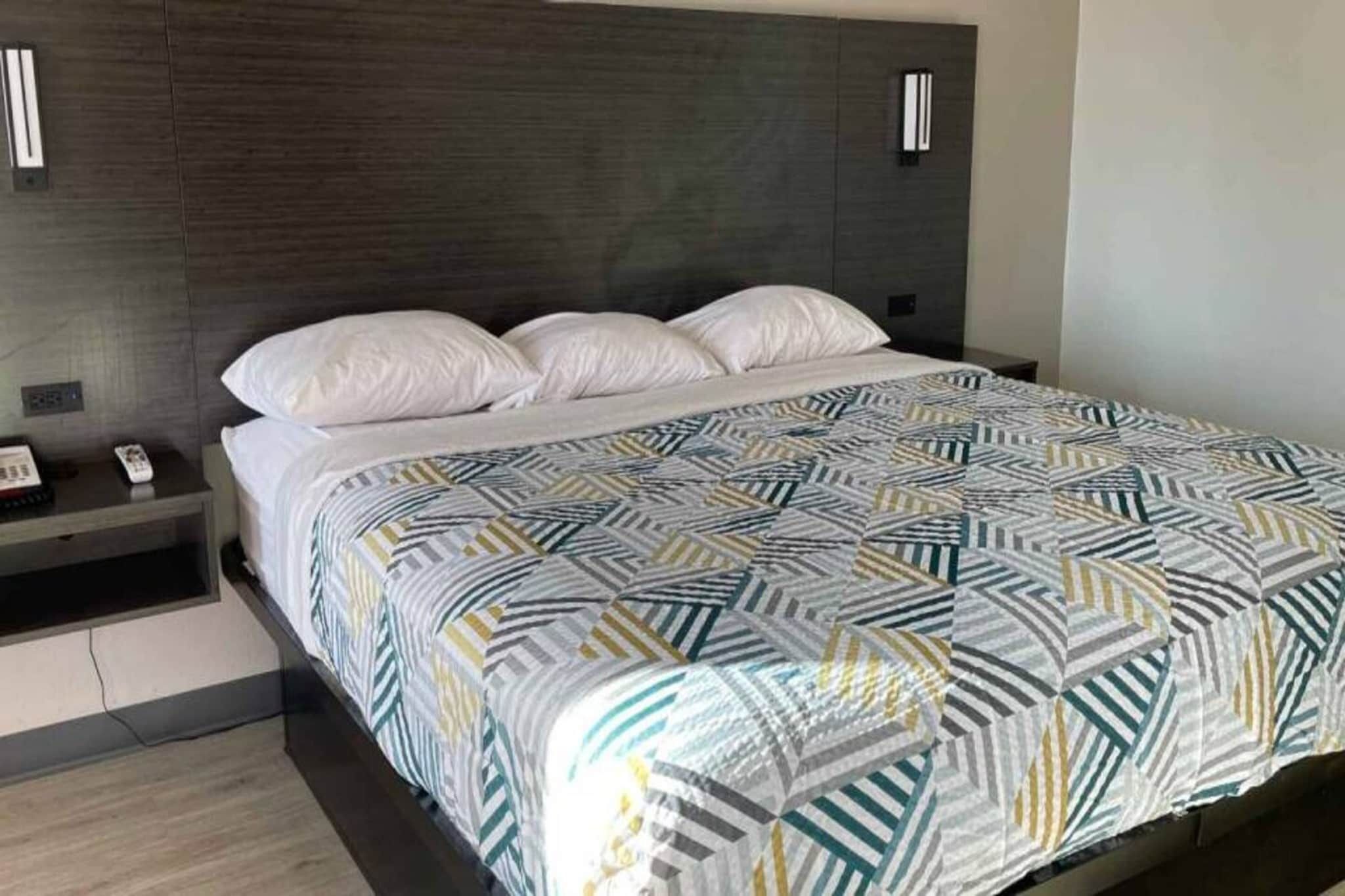 A hotel room with a bed, a nightstand, and a wall-mounted telephone.