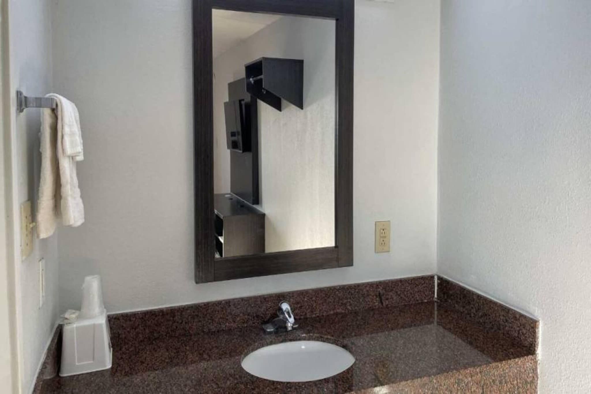 A bathroom with a white sink, dark granite countertop, and a mirror above the sink.