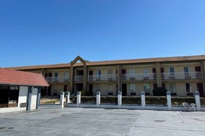 A hotel with a central courtyard, multiple balconies, and a red-roofed building to the left. - 1 King Bed | Nsmk, Micfridge (Stockbridge)