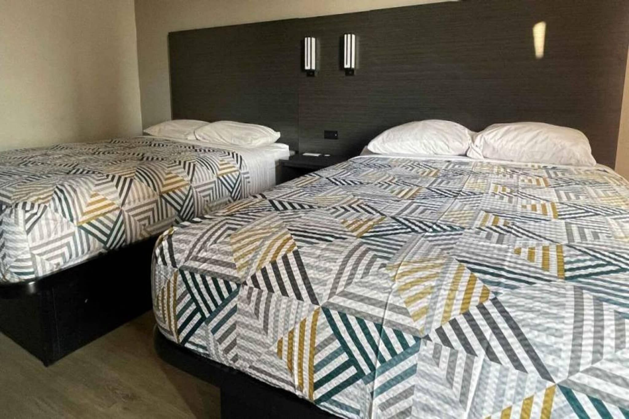 Habitación de hotel con dos camas individuales y una cama más grande, todas con ropa de cama estampada.
