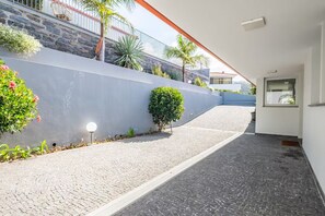 A paved pathway leading to a building with a stone wall and plants. - Vila Bela by Your Madeira Rentals (Arco da Calheta)