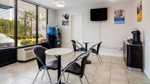 A hotel room with a dining area, a water dispenser, a flat-screen TV, and a window with blinds. - Comfy Full Beds|Free Wifi &Parking (LaGrange)