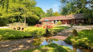 A rustic building with a red facade, a small bridge, and a stream.
