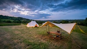 A campsite with two tents and a table set up under a canopy.