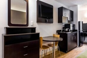 A compact kitchen with a dining area, including a table with chairs, a microwave, and cabinets.