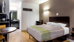 A hotel room with a bed, bedside table, and a desk with a chair. - Comfy Queen Bed|Free Wifi &Parking (LaGrange)