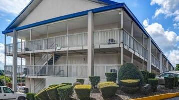 Un edificio de varios pisos con balcones, una escalera y un estacionamiento.