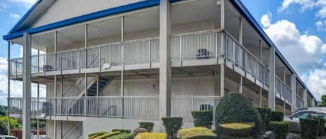 Um edifício com vários andares, varandas, escadaria e área de estacionamento.