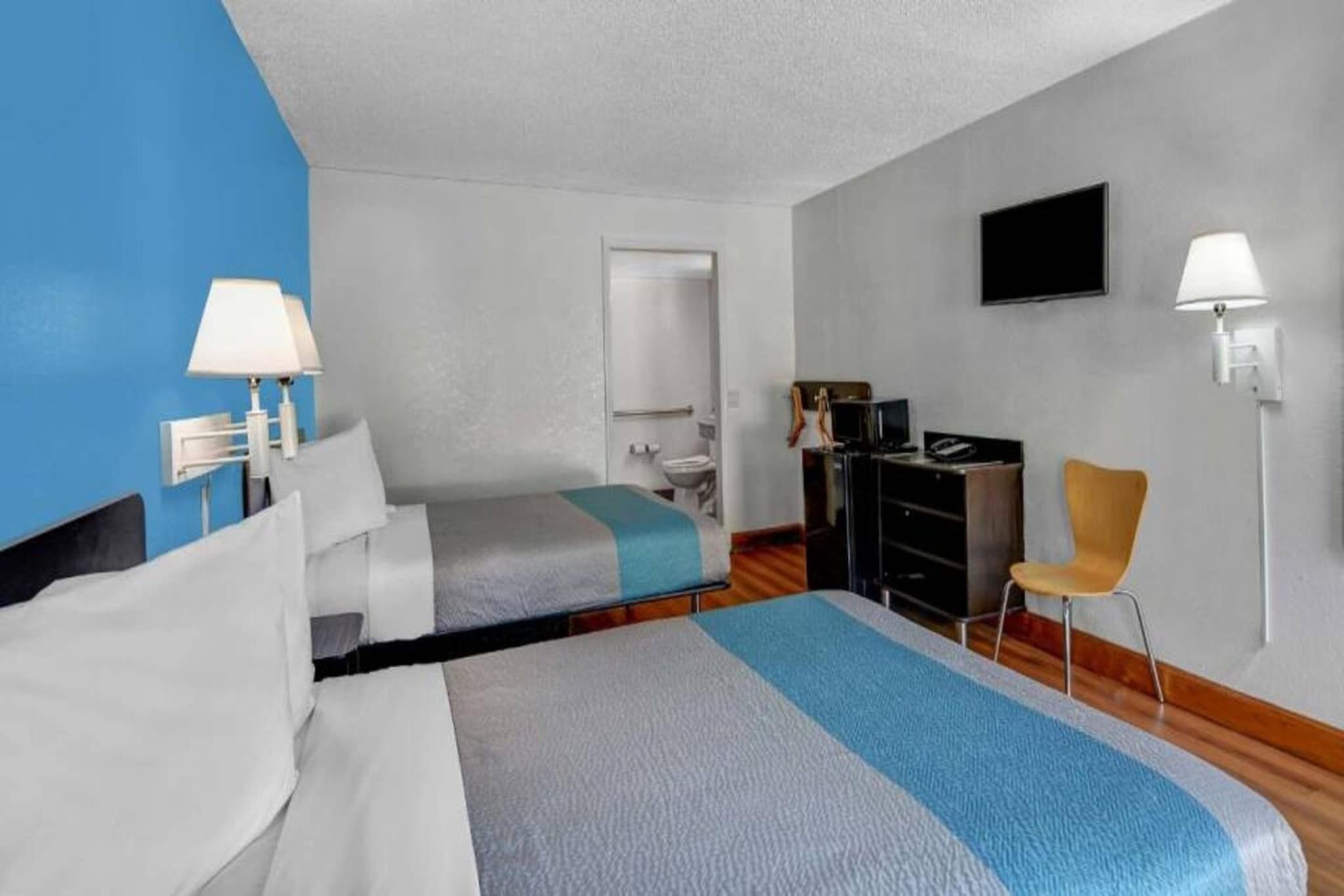 A hotel room with a bed, a desk, a chair, a TV, and a bathroom.