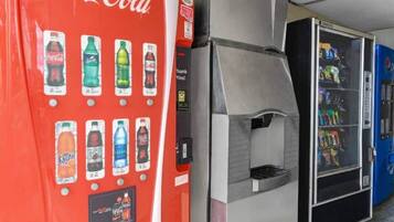 Ein Getränkeautomat, ein Mülleimer und ein Automat für Snacks.
