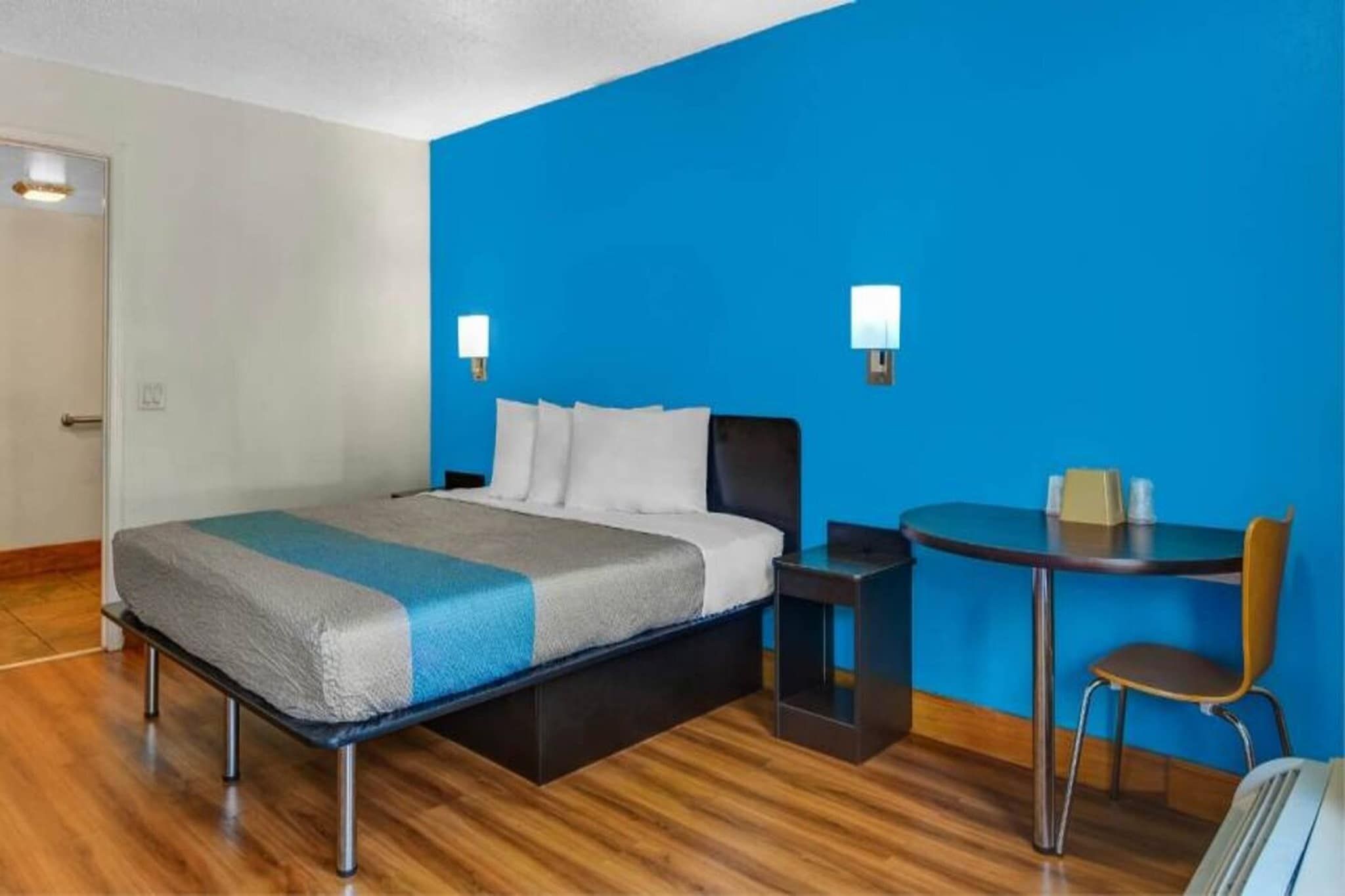 A hotel room with a bed, a desk, and a chair.