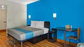 A hotel room with a bed, a desk, and a chair.