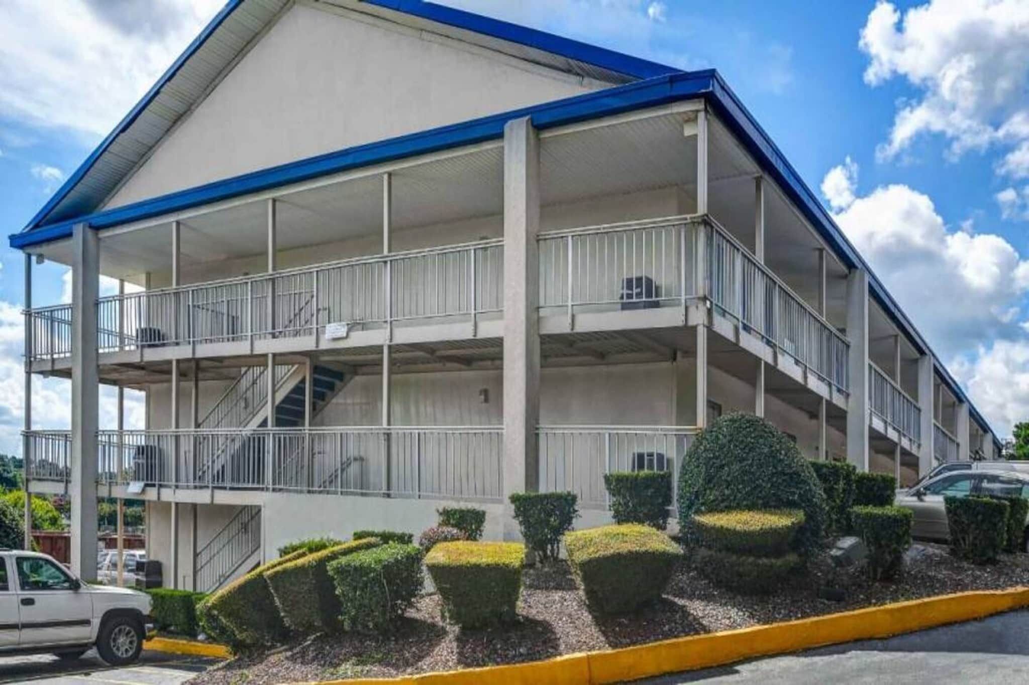Un edificio de varios pisos con balcones, una escalera y un estacionamiento.