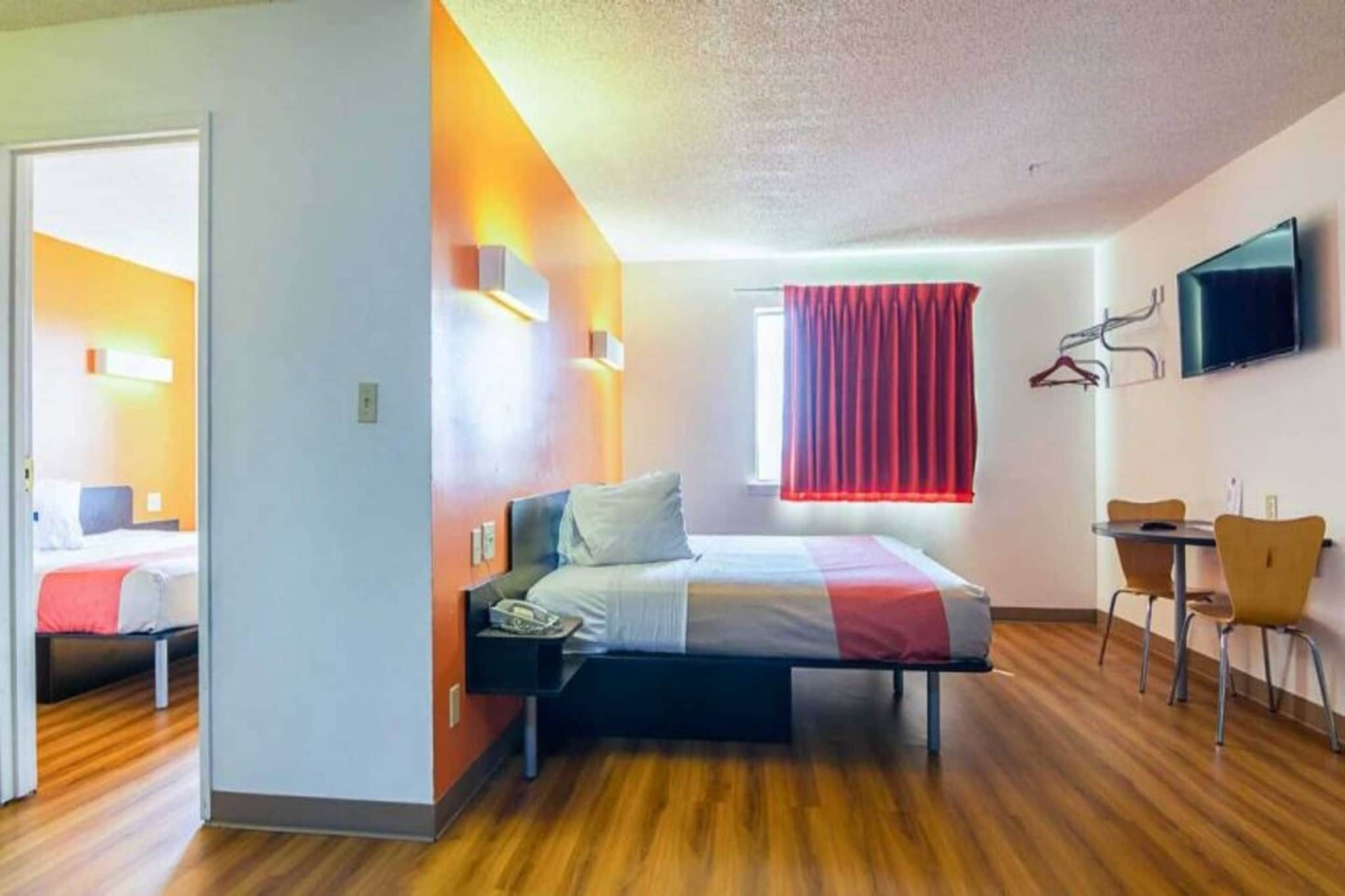 Quarto de hotel com cama, escrivaninha e televisão.