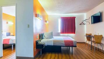 Quarto de hotel com cama, escrivaninha e televisão.