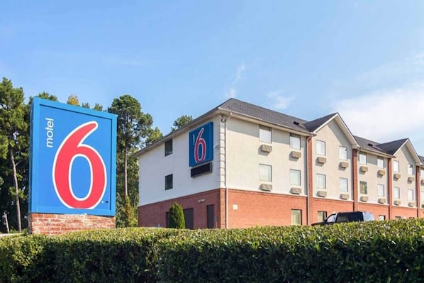 Et motel med et tydeligt skilt med '6', en murstensfacade og flere vinduer.