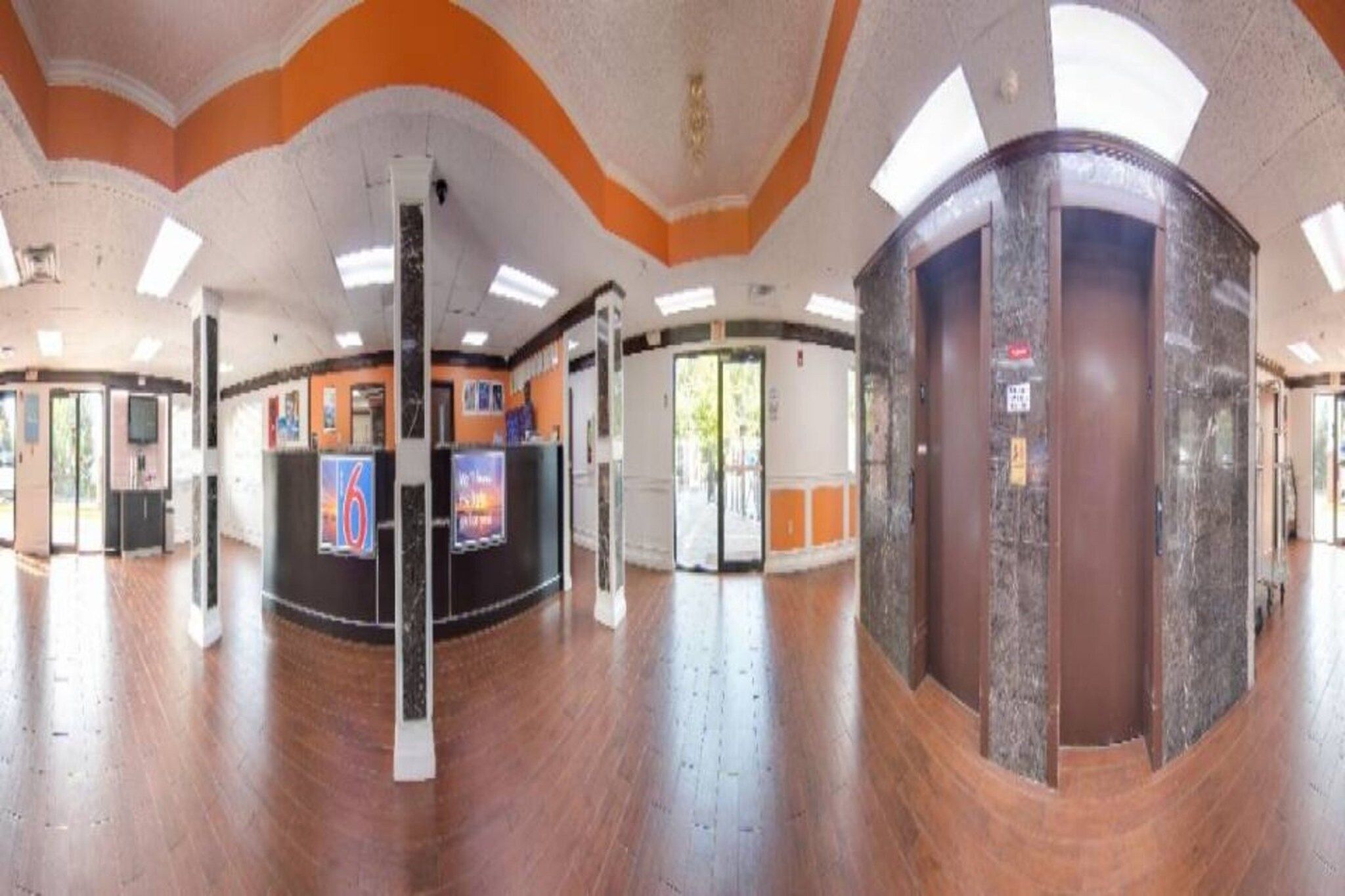 A spacious lobby with a curved reception desk, a large pillar, and a glass door leading outside.