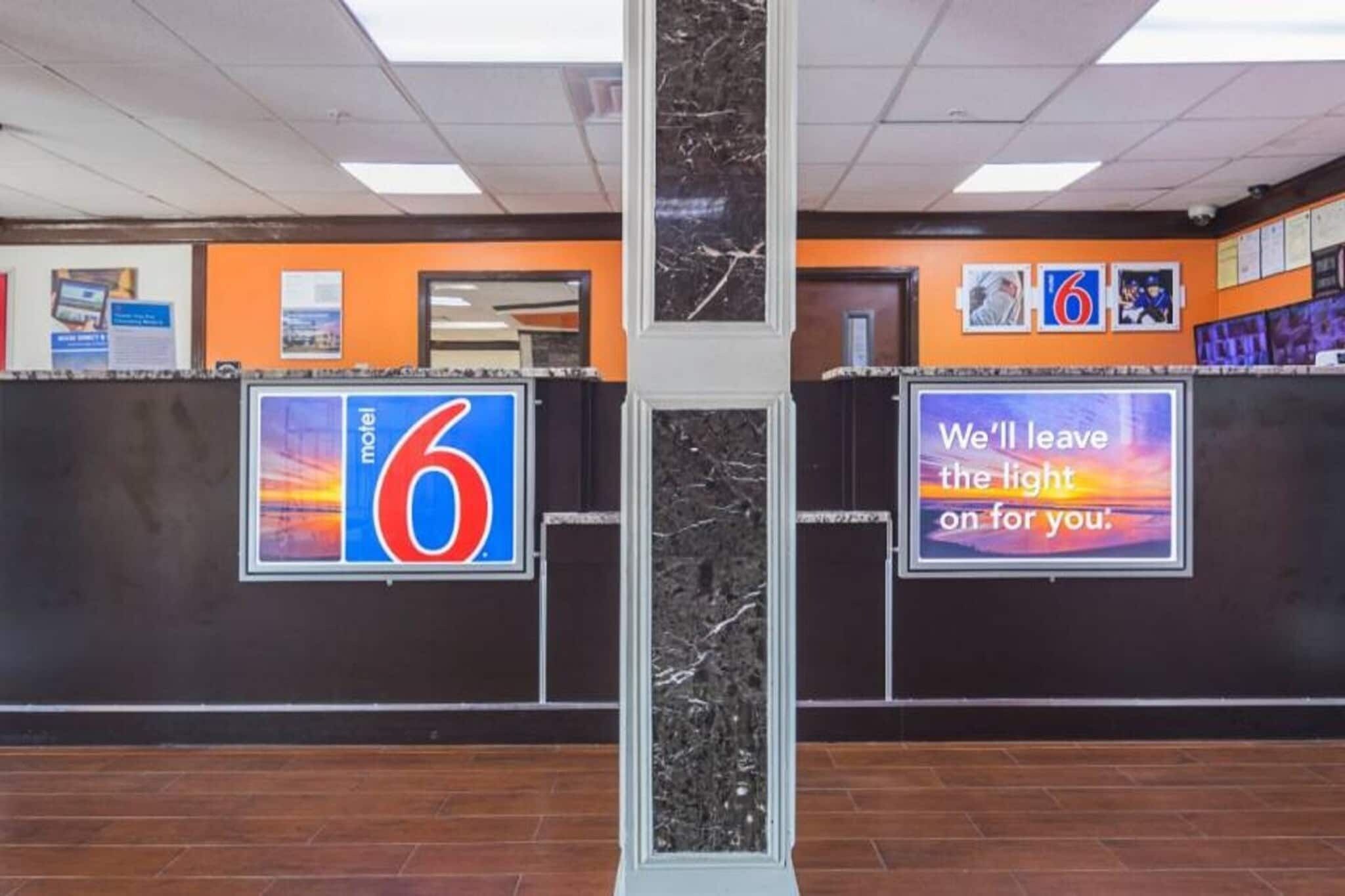 A hotel reception area with a '6' sign, a pillar, and a sign that says 'We'll leave the light on for you.'