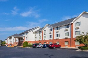 Et hotel med flere etager og en parkeringsplads foran.